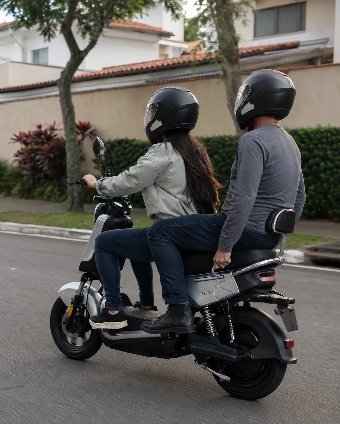 Duas pessoas de capacete andando juntas na VYA Tyme Pro por uma rua de bairro