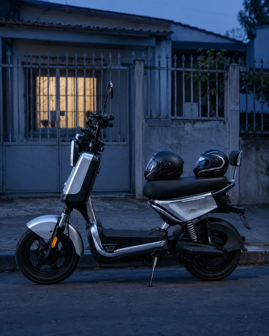 VYA Tyme Pro estacionada no portão de casa ao anoitecer, com dois capacetes no banco