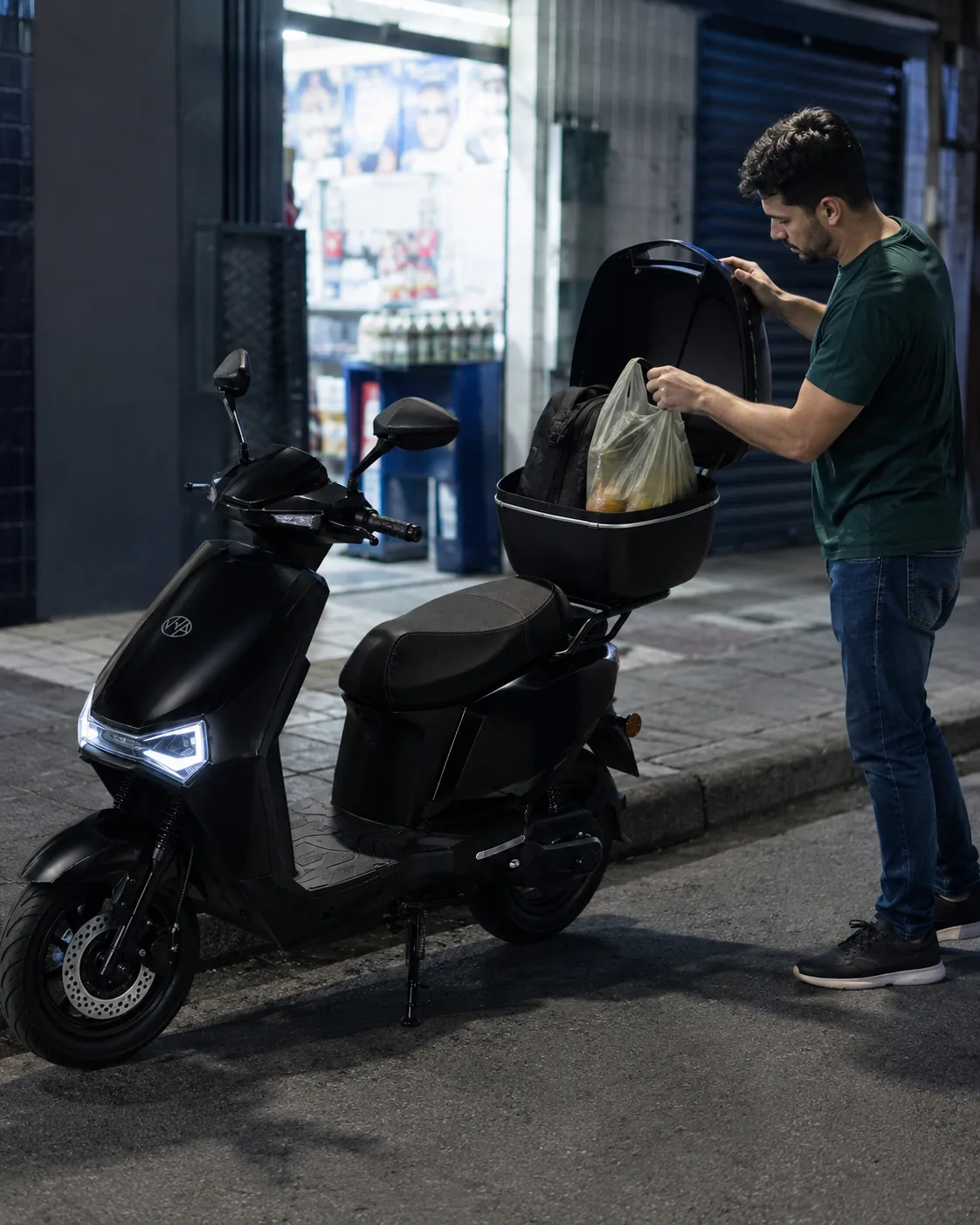 Homem guardando compras no baú da VYA Cyber em frente a um mercado à noite